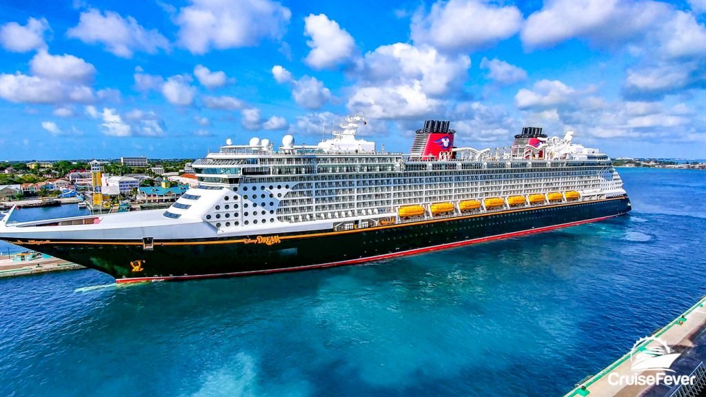 Disney cruise ship in clear blue water with blue sky and clouds